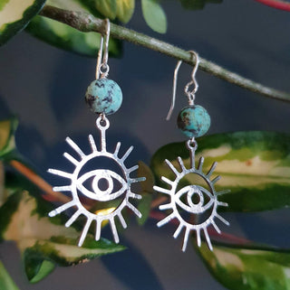 Charity fundraiser design to support the humanitarian crisis in Syria. Shimmering silver earrings with eye of protection design and turquoise beads. 'Himaya' ethical hand beaten stainless steel earrings by Nic Danning Jewellery.