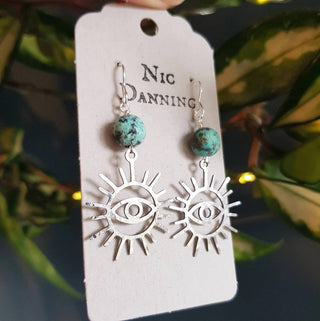 Charity fundraiser design to support the humanitarian crisis in Syria. Shimmering silver earrings with eye of protection design and turquoise beads. 'Himaya' ethical hand beaten stainless steel earrings by Nic Danning Jewellery.