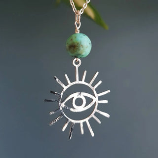 Charity fundraiser design to support the humanitarian crisis in Syria. Shimmering silver necklace with eye of protection design and turquoise bead. 'Himaya' ethical hand beaten stainless steel necklace by Nic Danning Jewellery.