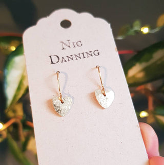Glowing gold earrings in tiny heart design. 'The Lovers, Clara' ethical hand beaten brass earrings by Nic Danning Jewellery.