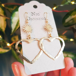 Glowing gold stud earrings in statement heart and sunstar design. 'The Lovers, Miranda' ethical hand beaten brass earrings by Nic Danning Jewellery.