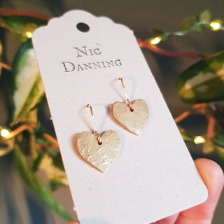 Glowing gold earrings in dainty heart design. 'The Lovers, Rosalind' ethical hand beaten brass earrings by Nic Danning Jewellery.