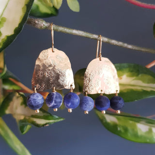 Glowing gold earrings with semi precious sodalite beadwork. 'Titans Astrape' ethical hand beaten brass earrings by Nic Danning Jewellery.