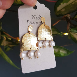 Glowing gold earrings with freshwater pearls. 'Titans Eos' ethical hand beaten brass earrings by Nic Danning Jewellery.