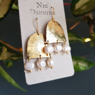Glowing gold earrings with freshwater pearls. 'Titans Eos' ethical hand beaten brass earrings by Nic Danning Jewellery.
