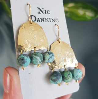 Glowing gold earrings with semi precious turquoise beadwork. 'Titans Gaia' ethical hand beaten brass earrings by Nic Danning Jewellery.