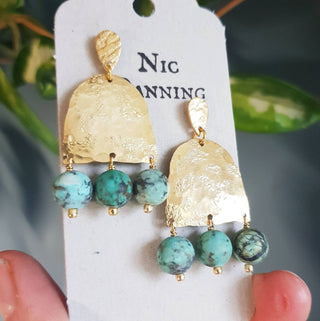 Glowing gold earrings with semi precious turquoise beadwork. 'Titans Gaia' ethical hand beaten brass earrings by Nic Danning Jewellery.