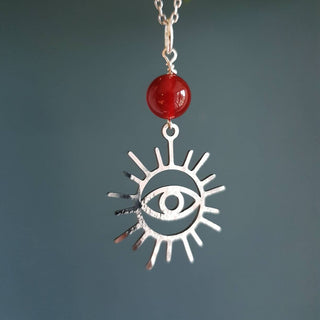 Charity fundraiser design to support the humanitarian crisis in Syria. Shimmering silver necklace with eye of protection design and carnelian bead. 'Himaya' ethical hand beaten stainless steel necklace by Nic Danning Jewellery.