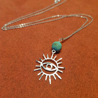 Charity fundraiser design to support the humanitarian crisis in Syria. Shimmering silver necklace with eye of protection design and turquoise bead. 'Himaya' ethical hand beaten stainless steel necklace by Nic Danning Jewellery.