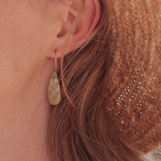 Glowing gold earrings in teardrop design. 'Tempest Ros' ethical hand beaten brass earrings by Nic Danning Jewellery.