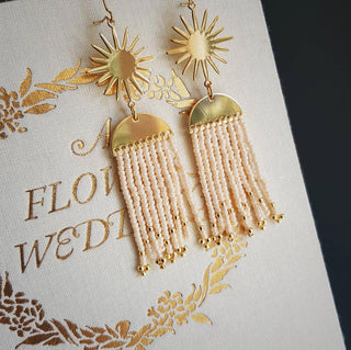 Glowing gold celestial earrings with fine Japanese glass beads in Ivory Pearl. 'Hera Oracle' gold plated brass and hand beaded earrings by Nic Danning Jewellery.
