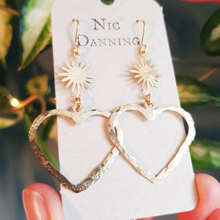Glowing gold stud earrings in statement heart and sunstar design. 'The Lovers, Miranda' ethical hand beaten brass earrings by Nic Danning Jewellery.