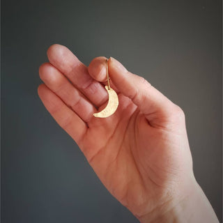 Glowing gold earrings in dainty crescent moon design. 'Gossamer Demi Lune' ethical hand beaten brass earrings by Nic Danning Jewellery.
