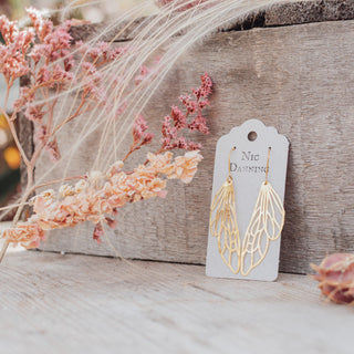 Glowing gold earrings in cutout dragonfly wing design. 'Gossamer Dryad' ethical hand beaten brass earrings by Nic Danning Jewellery.