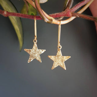 Glowing gold earrings in dainty star design. 'Tempest Stella' ethical hand beaten brass earrings by Nic Danning Jewellery.