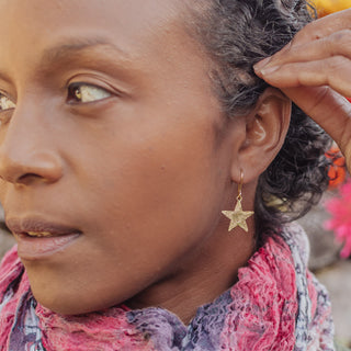 Glowing gold earrings in dainty star design. 'Tempest Stella' ethical hand beaten brass earrings by Nic Danning Jewellery.