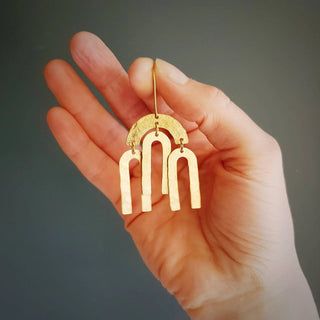 Glowing gold earrings in statement hanging arcs design. 'Tempest Rainbow' ethical hand beaten brass earrings by