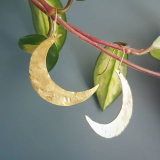 Glowing gold earrings in statement crescent moon design. 'Tempest Artemis' ethical hand beaten brass earrings by Nic Danning Jewellery.
