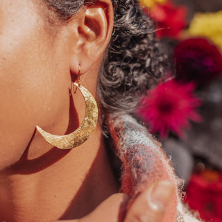Glowing gold earrings in statement crescent moon design. 'Tempest Artemis' ethical hand beaten brass earrings by Nic Danning Jewellery.