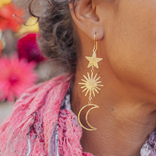Glowing gold earrings in cascading celestial design. 'Tempest Celestial' ethical hand beaten brass earrings by Nic Danning Jewellery.