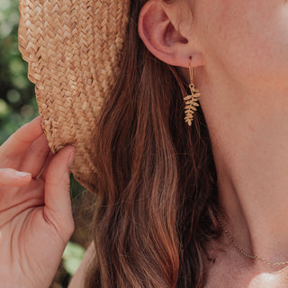Glowing gold earrings in delicate fern design. 'Tempest Folia' ethical hand beaten brass earrings by Nic Danning Jewellery.