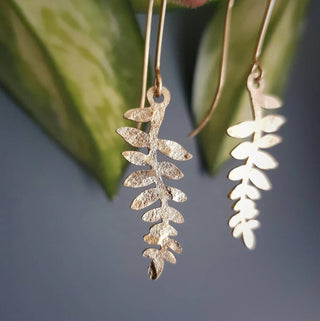 Glowing gold earrings in delicate fern design. 'Tempest Folia' ethical hand beaten brass earrings by Nic Danning Jewellery.