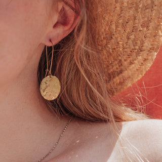 Glowing gold drop earrings in statement disc design. 'Tempest Helios' ethical hand beaten brass earrings by Nic Danning Jewellery.