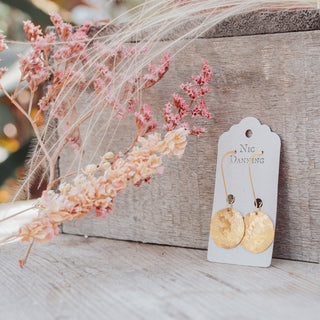 Glowing gold drop earrings in statement disc design. 'Tempest Helios' ethical hand beaten brass earrings by Nic Danning Jewellery.