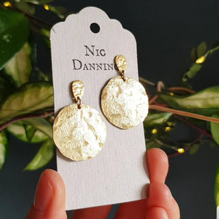 Glowing gold stud earrings in statement disc design. 'Tempest Helios' ethical hand beaten brass earrings by Nic Danning Jewellery.