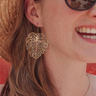 Statement monstera leaf design, glowing gold earrings. 'Tempest Monsoon' ethical hand beaten brass earrings by Nic Danning Jewellery.
