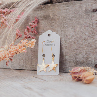 Glowing gold drop earrings in statement star design. 'Tempest Supernova' ethical hand beaten brass earrings by Nic Danning Jewellery.