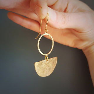 Glowing gold earrings in an abstract geometric design. 'Tempest Umbra' ethical hand beaten brass earrings by Nic Danning Jewellery.