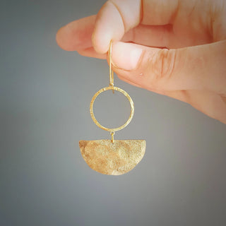 Glowing gold earrings in an abstract geometric design. 'Tempest Umbra' ethical hand beaten brass earrings by Nic Danning Jewellery.