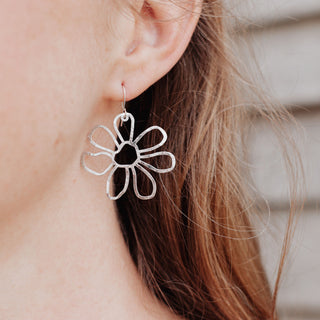 Shimmering silver earrings in cutout floral design. 'Gossamer Chloris' ethical hand beaten stainless steel earrings by Nic Danning Jewellery.