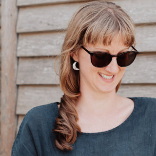 Shimmering silver earrings in dainty crescent moon design. 'Gossamer Demi Lune' ethical hand beaten stainless steel earrings by Nic Danning Jewellery.