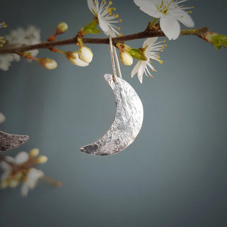 Shimmering silver earrings in dainty crescent moon design. 'Gossamer Demi Lune' ethical hand beaten stainless steel earrings by Nic Danning Jewellery.