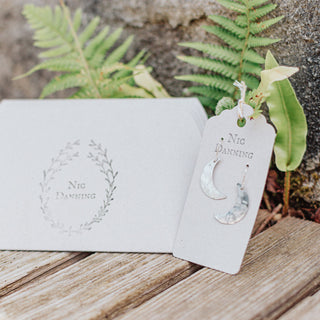 Shimmering silver earrings in dainty crescent moon design. 'Gossamer Demi Lune' ethical hand beaten stainless steel earrings by Nic Danning Jewellery.