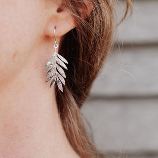 Shimmering silver earrings in botanical leaf design. 'Gossamer Athena' ethical hand beaten stainless steel earrings by Nic Danning Jewellery.