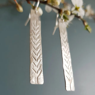 Shimmering silver earrings in botanical bar design. 'Gossamer Ceres' ethical hand beaten stainless steel earrings by Nic Danning Jewellery.
