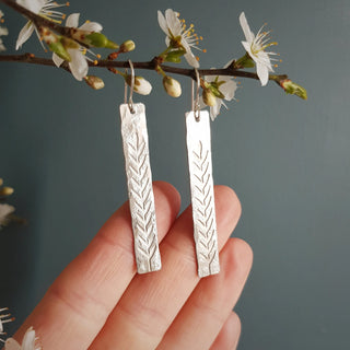 Shimmering silver earrings in botanical bar design. 'Gossamer Ceres' ethical hand beaten stainless steel earrings by Nic Danning Jewellery.