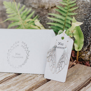 Shimmering silver earrings in cutout dragonfly wing design. 'Gossamer Dryad' ethical hand beaten stainless steel earrings by Nic Danning Jewellery.