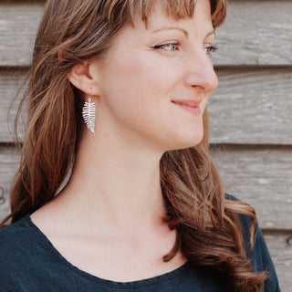 Shimmering silver earrings in botanical fern leaf design. 'Gossamer Fern' ethical hand beaten stainless steel earrings by Nic Danning Jewellery.