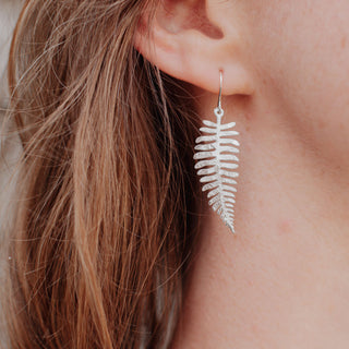 Shimmering silver earrings in botanical fern leaf design. 'Gossamer Fern' ethical hand beaten stainless steel earrings by Nic Danning Jewellery.