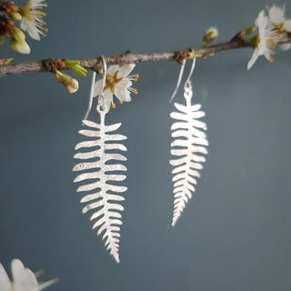 Shimmering silver earrings in botanical fern leaf design. 'Gossamer Fern' ethical hand beaten stainless steel earrings by Nic Danning Jewellery.
