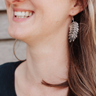 Shimmering silver earrings in botanical cutout leaf design. 'Gossamer Hebe' ethical hand beaten stainless steel earrings by Nic Danning Jewellery.