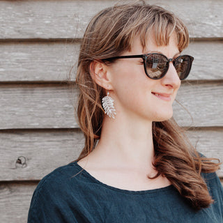 Shimmering silver earrings in botanical cutout leaf design. 'Gossamer Hebe' ethical hand beaten stainless steel earrings by Nic Danning Jewellery.