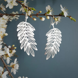 Shimmering silver earrings in botanical cutout leaf design. 'Gossamer Hebe' ethical hand beaten stainless steel earrings by Nic Danning Jewellery.