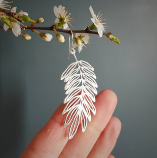 Shimmering silver earrings in botanical cutout leaf design. 'Gossamer Hebe' ethical hand beaten stainless steel earrings by Nic Danning Jewellery.