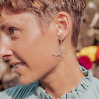 Shimmering silver earrings in botanical crescent moon design. 'Gossamer Selene' ethical hand beaten stainless steel earrings by Nic Danning Jewellery.