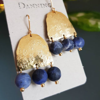 Glowing gold earrings with semi precious sodalite beadwork. 'Titans Astrape' ethical hand beaten brass earrings by Nic Danning Jewellery.